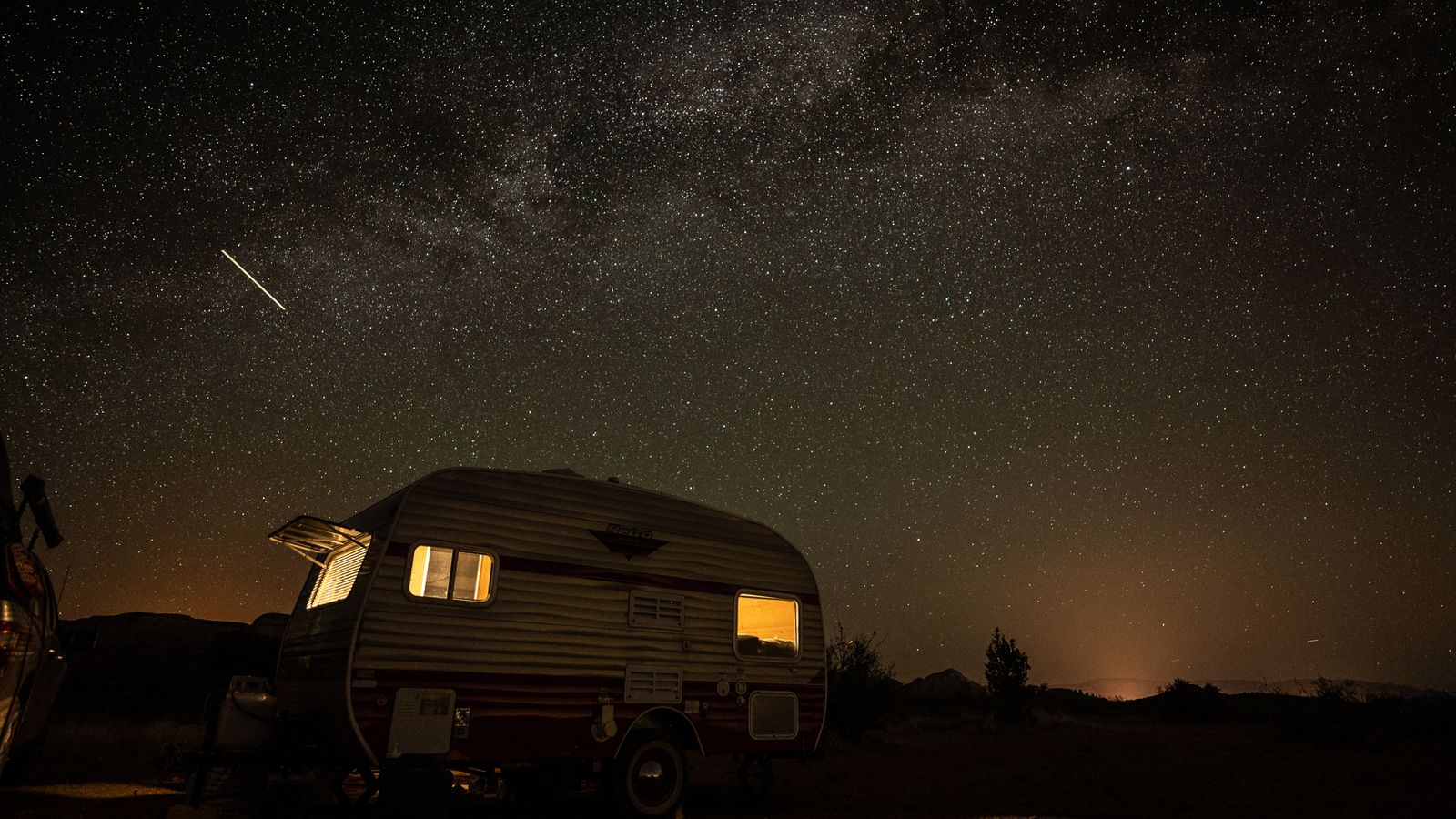 A camper beneath the night sky and a shooting star, photo by ken choi on Pexels