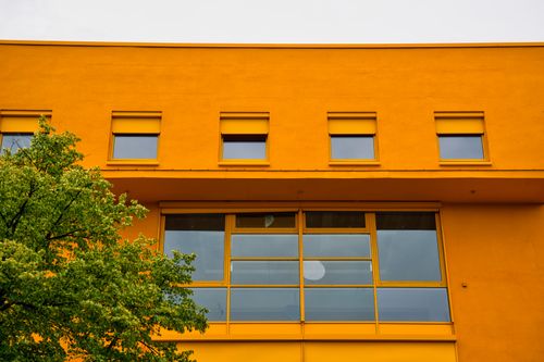 Free Bold orange building facade with green tree in Berlin, Germany. Stock Photo