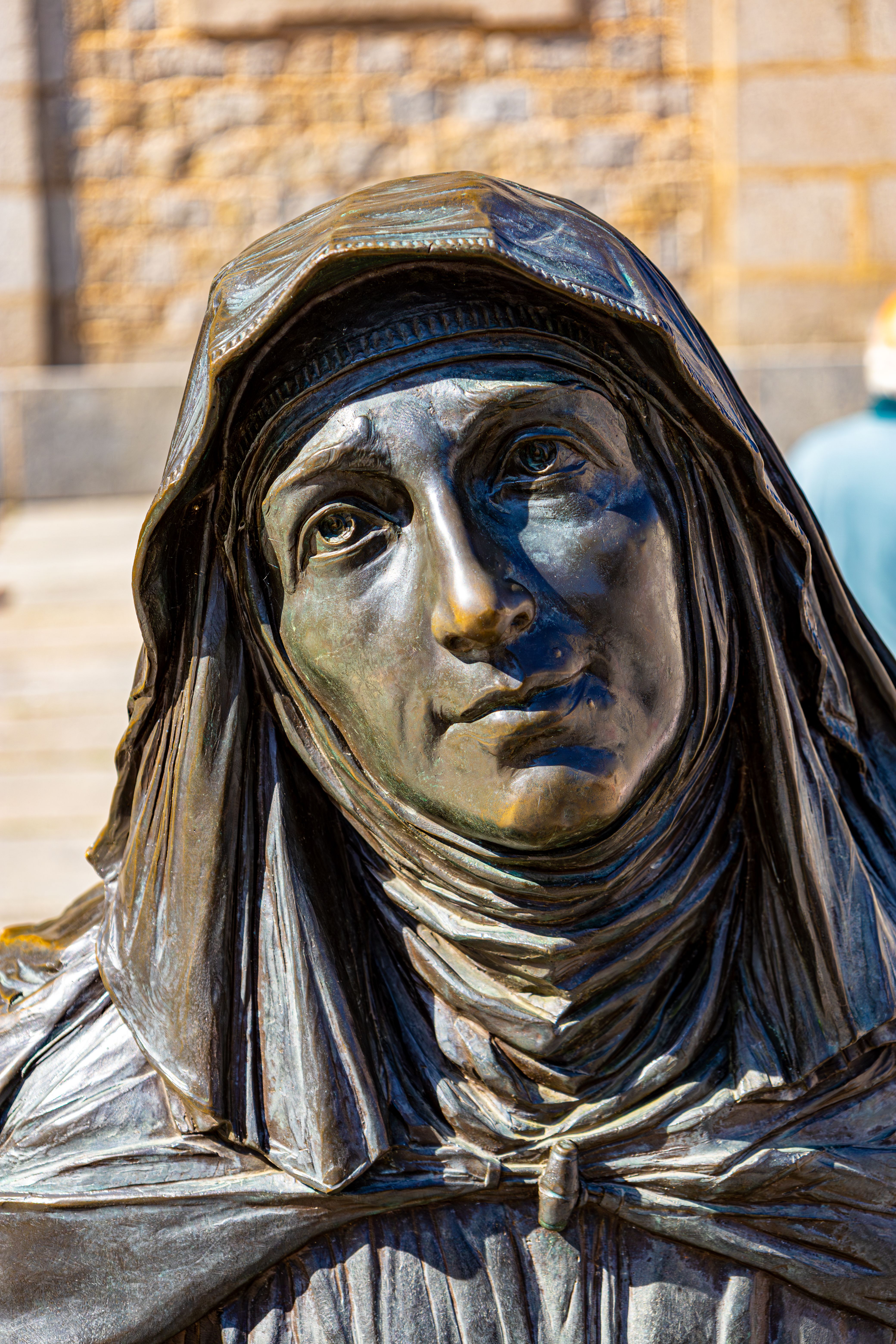 Close-up of a bronze statue depicting a nun in Ávila, Spain, outdoors.