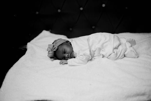 Serene black and white photo of a sleeping newborn baby on a soft blanket.
