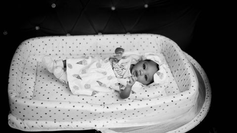 Black and white photo of a newborn baby lying in a comfortable crib.