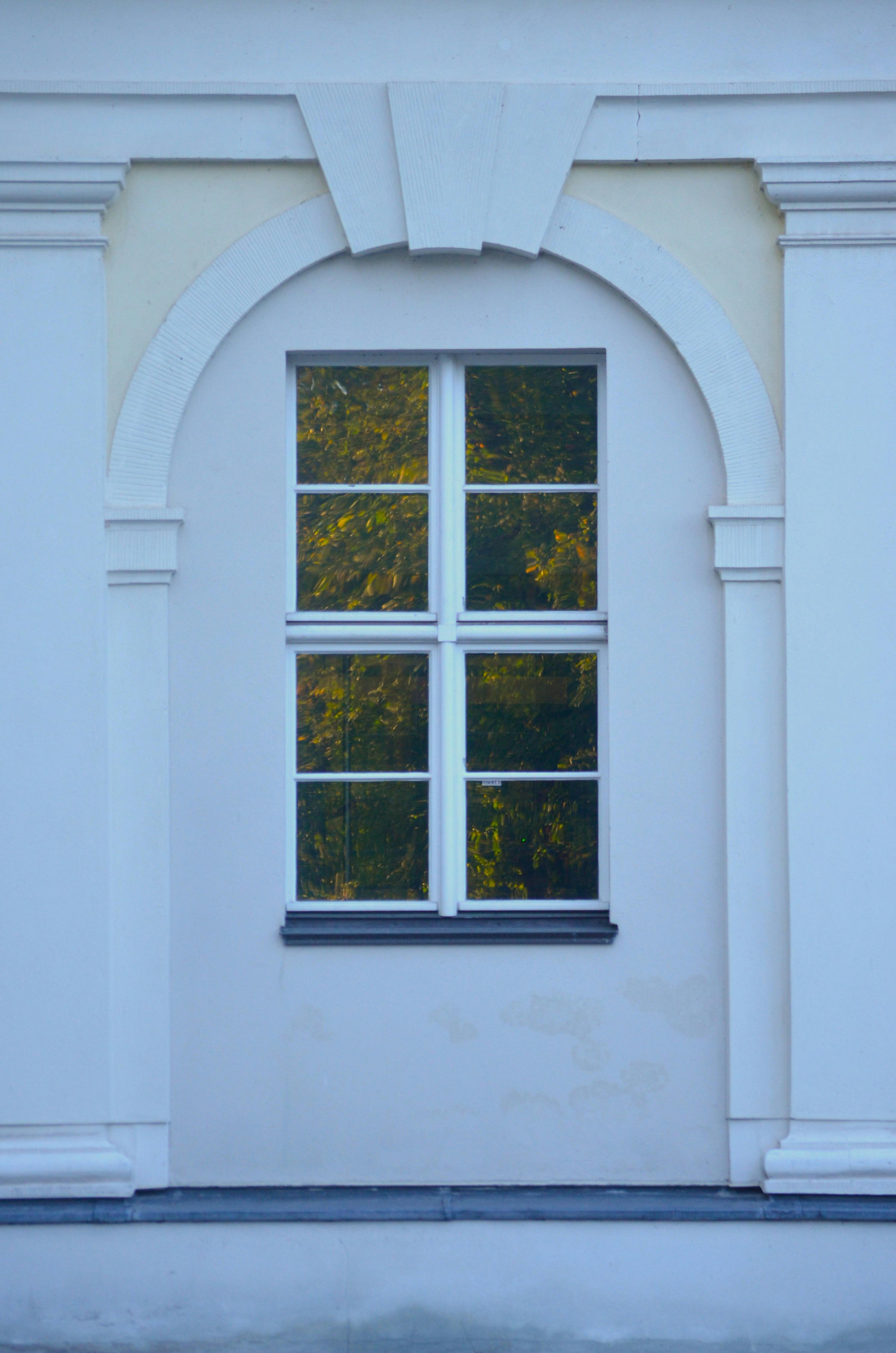 gratis Een klassiek raam met een boogframe waarin de herfstkleuren worden weerspiegeld. Stockfoto