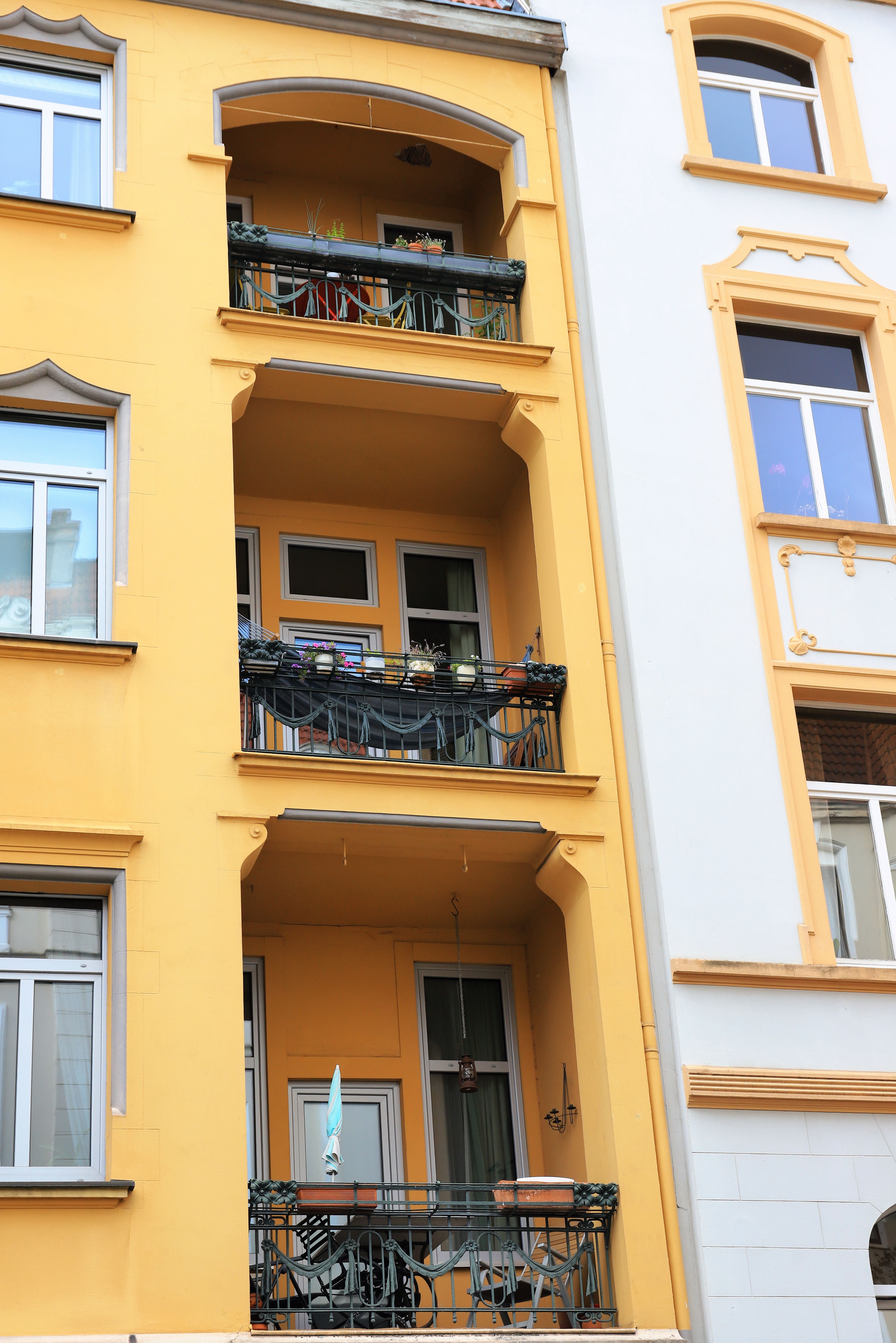 Free Vibrant yellow facade with ornate balconies and windows in a European city center. Stock Photo