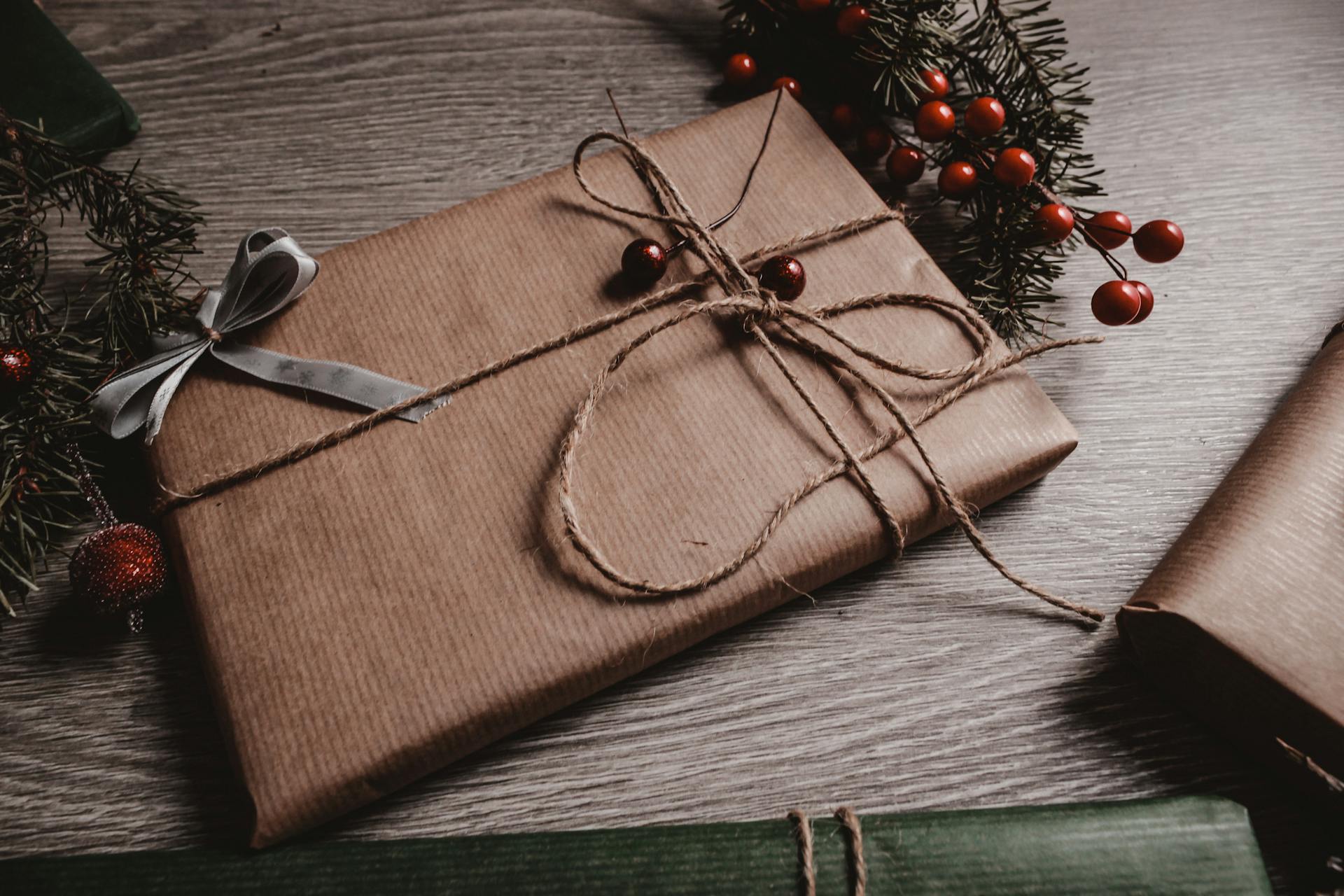 A beautifully wrapped Christmas gift with twine and natural elements on a rustic table.
