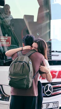 A heartfelt farewell between two people hugging near a bus station. Emotional goodbye.