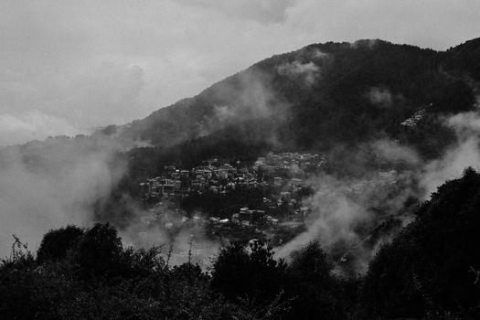 Atmospheric black and white photo of misty hills in Himachal Pradesh, India.
