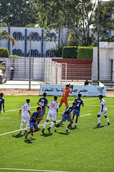 A group of young athletes playing soccer on a vibrant outdoor field with lush surroundings.