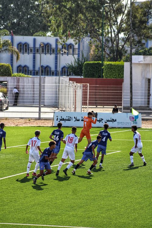 Free A group of young athletes playing soccer on a vibrant outdoor field with lush surroundings. Stock Photo
