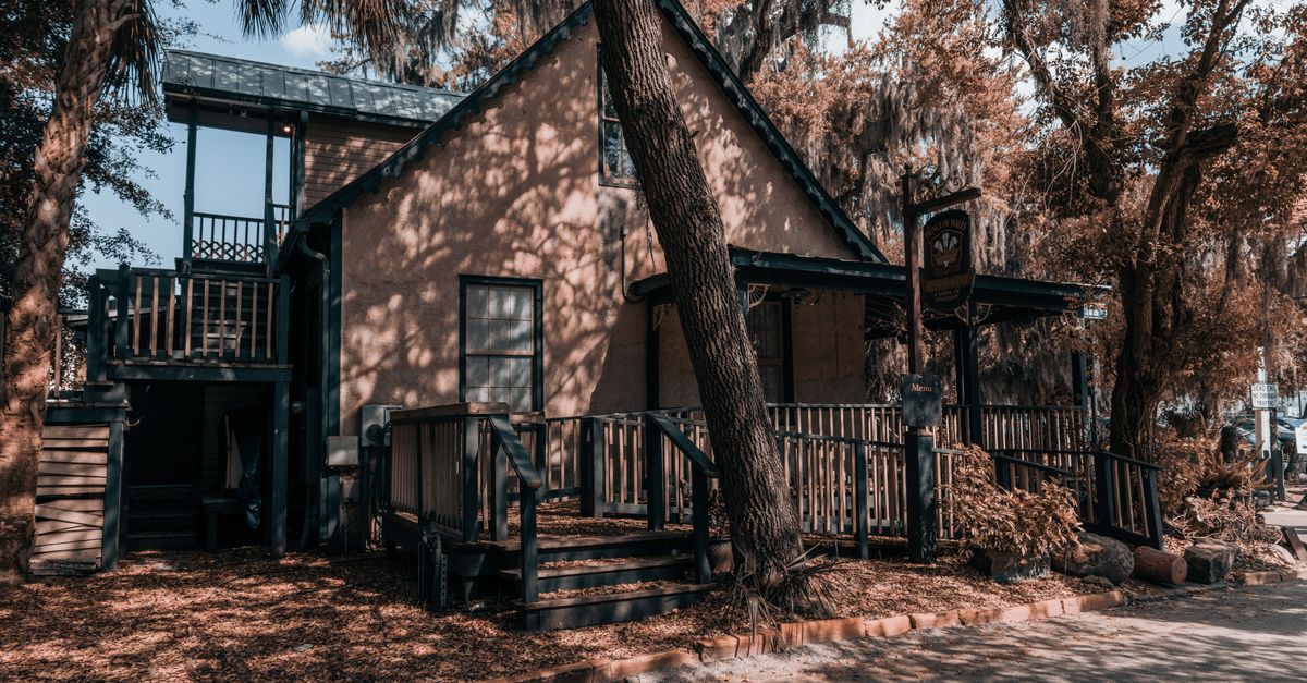 A rustic, quaint vintage house surrounded by lush trees, captured in Hollywood, Florida.