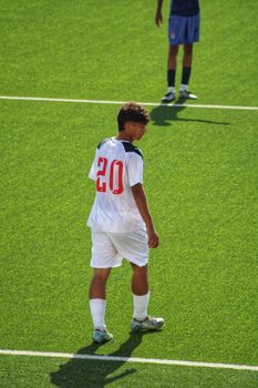 Teen soccer player on the field in white jersey with number 20, ready to play.