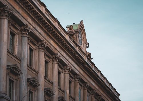 Free A detailed view of neoclassical architecture with ornate columns and clock in Milan, Italy. Stock Photo