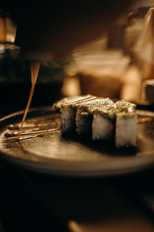 Free Close-up of a gourmet sushi roll being artfully drizzled with sauce, showcasing culinary elegance. Stock Photo