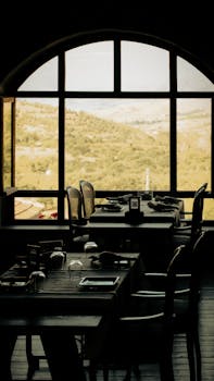 Elegant indoor dining with scenic mountain view through arched windows.