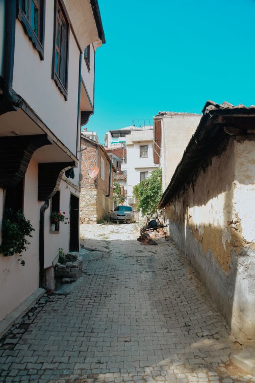 Free A quaint alley in a historic neighborhood with old buildings and vibrant blue sky. Stock Photo