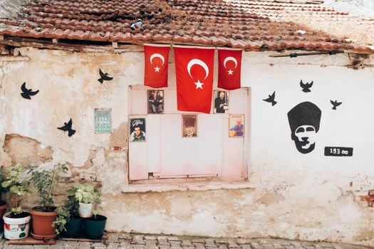 Rustic wall with Turkish flags, portraits, and bird art. Historic and cultural ambiance.
