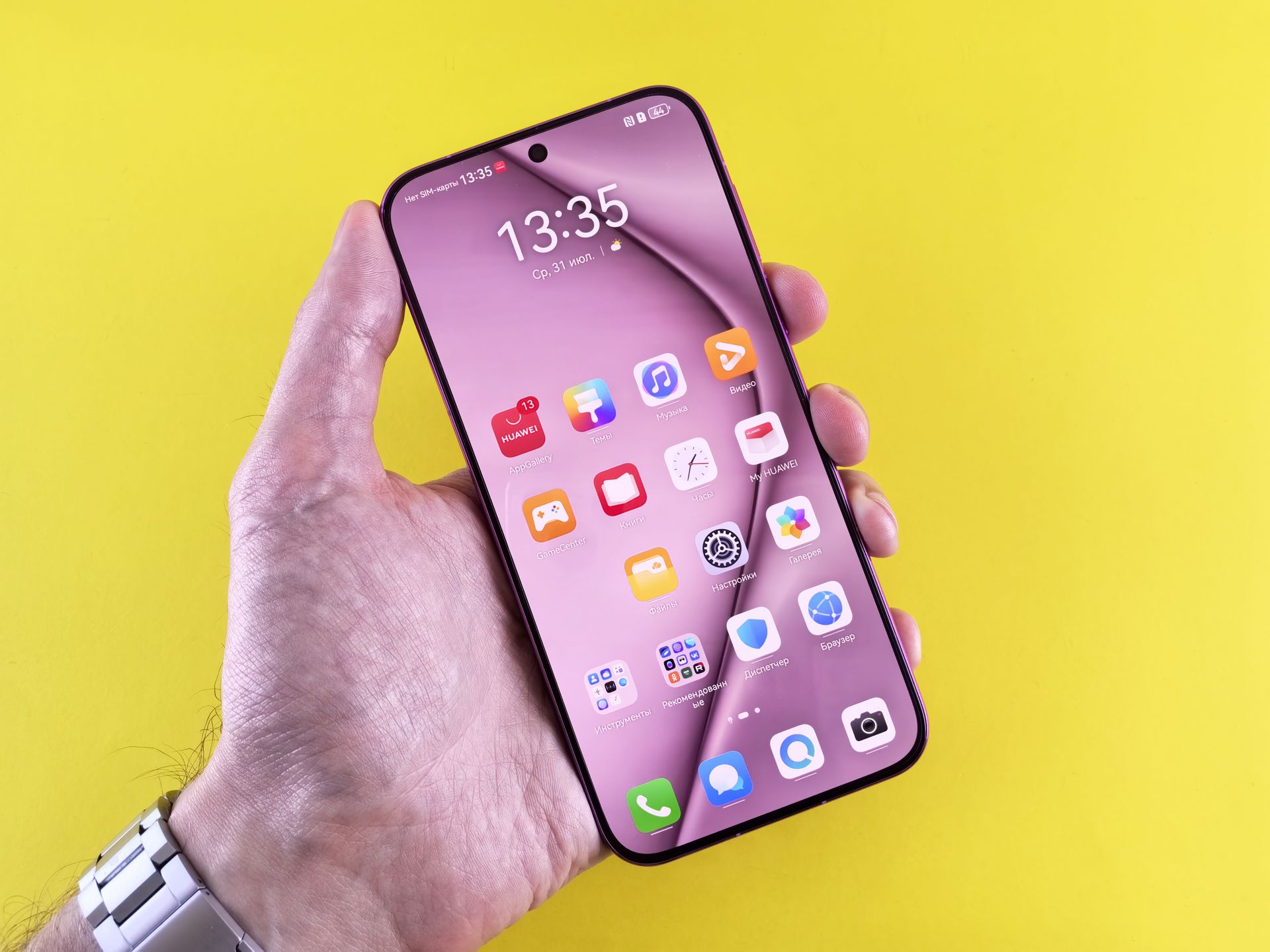 Person holding a smartphone with apps displayed on pink screen, yellow background.