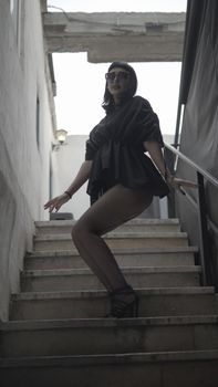 Fashionable woman in modern outfit posing confidently on a staircase in an urban setting.