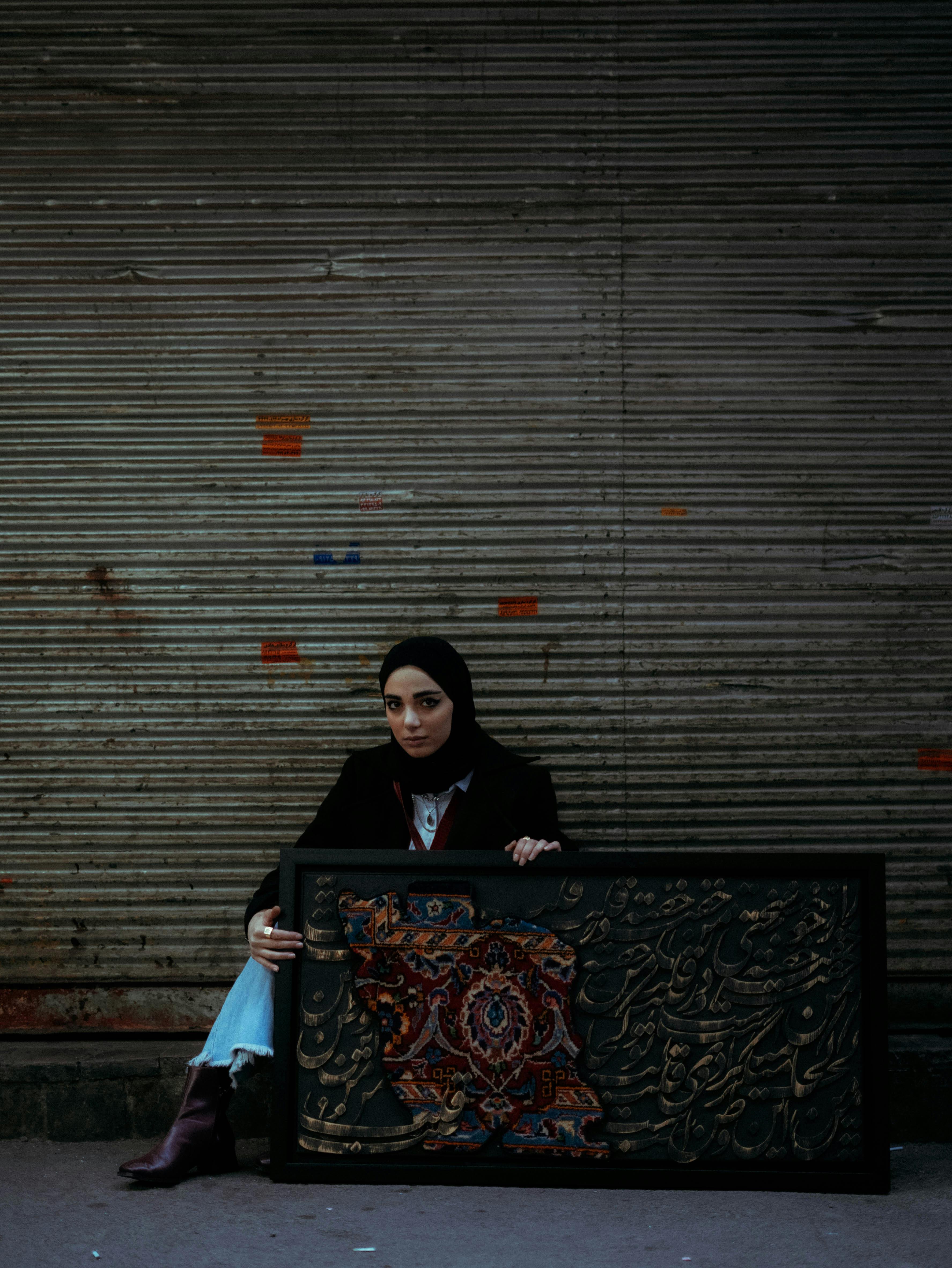 Woman in hijab holding ornate frame against urban backdrop