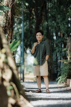 Person leisurely walking on a sunlit path surrounded by greenery.