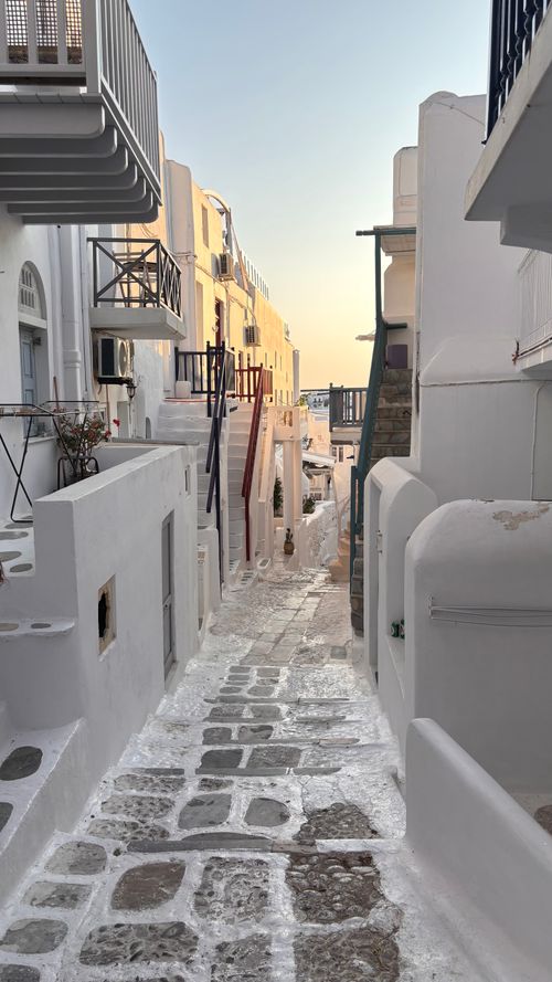Free Picturesque narrow alley in a Greek island with whitewashed buildings during sunset. Stock Photo