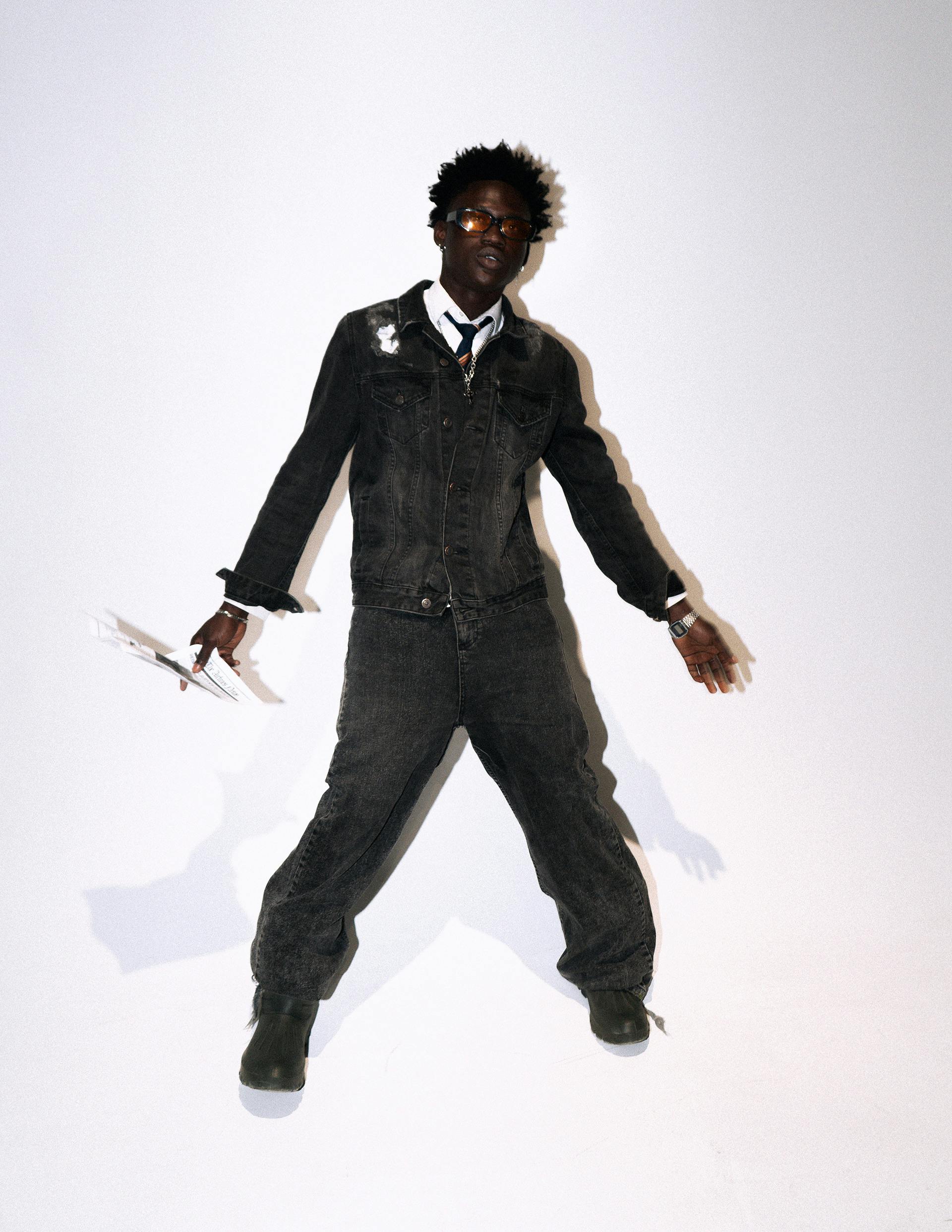 Person in fashionable denim clothing striking a dynamic pose against a white background.