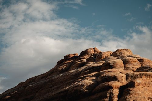 Free Sunlit red rock formation in Utah with dramatic clouds and blue sky. Stock Photo