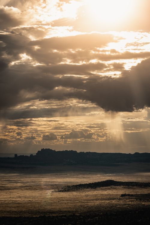Free A breathtaking view of the Utah desert with dramatic clouds and sunlight breaking through at sunset. Stock Photo