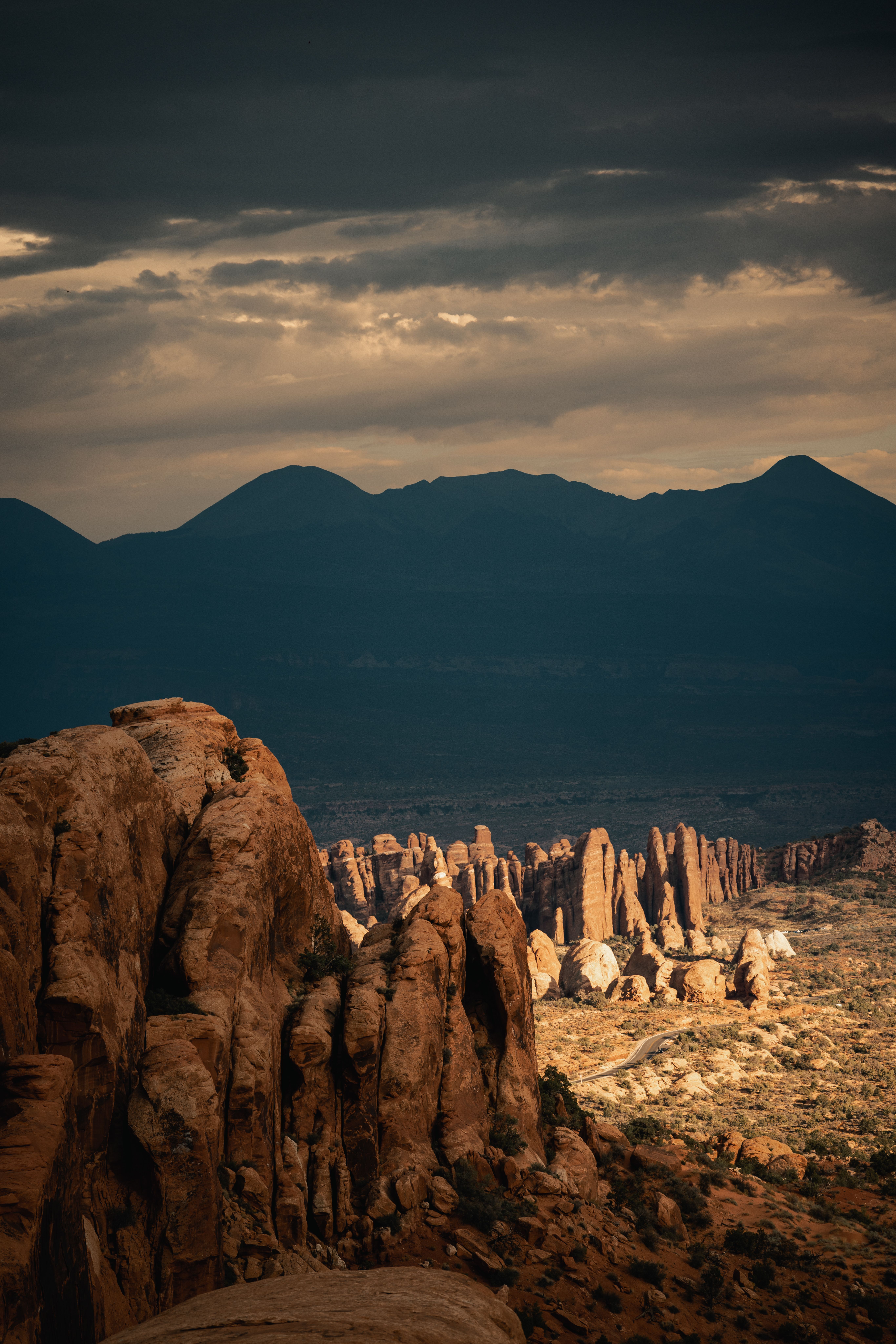 Dramatic sunset over rock formations in Utah's desert landscape, showcasing nature's rugged beauty.