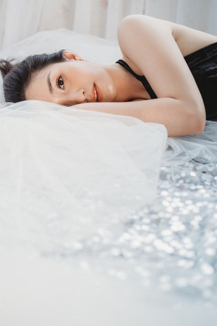 A serene portrait of a woman in black lingerie reclining on a bed, showcasing elegance and relaxation.
