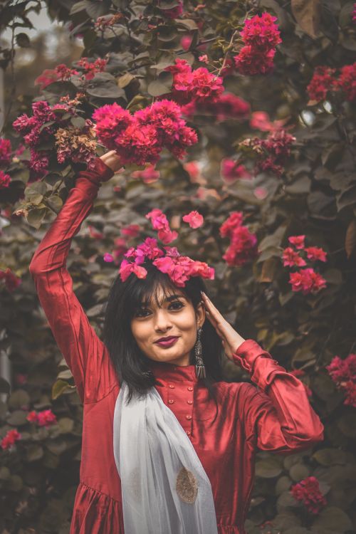 Free A woman in traditional attire poses gracefully amidst blooming flowers. Stock Photo