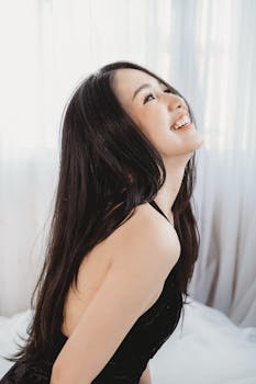 一位女士在自然光下摆出优雅的姿势，微笑着凸显出她在室内的五官，散发着幸福和美丽