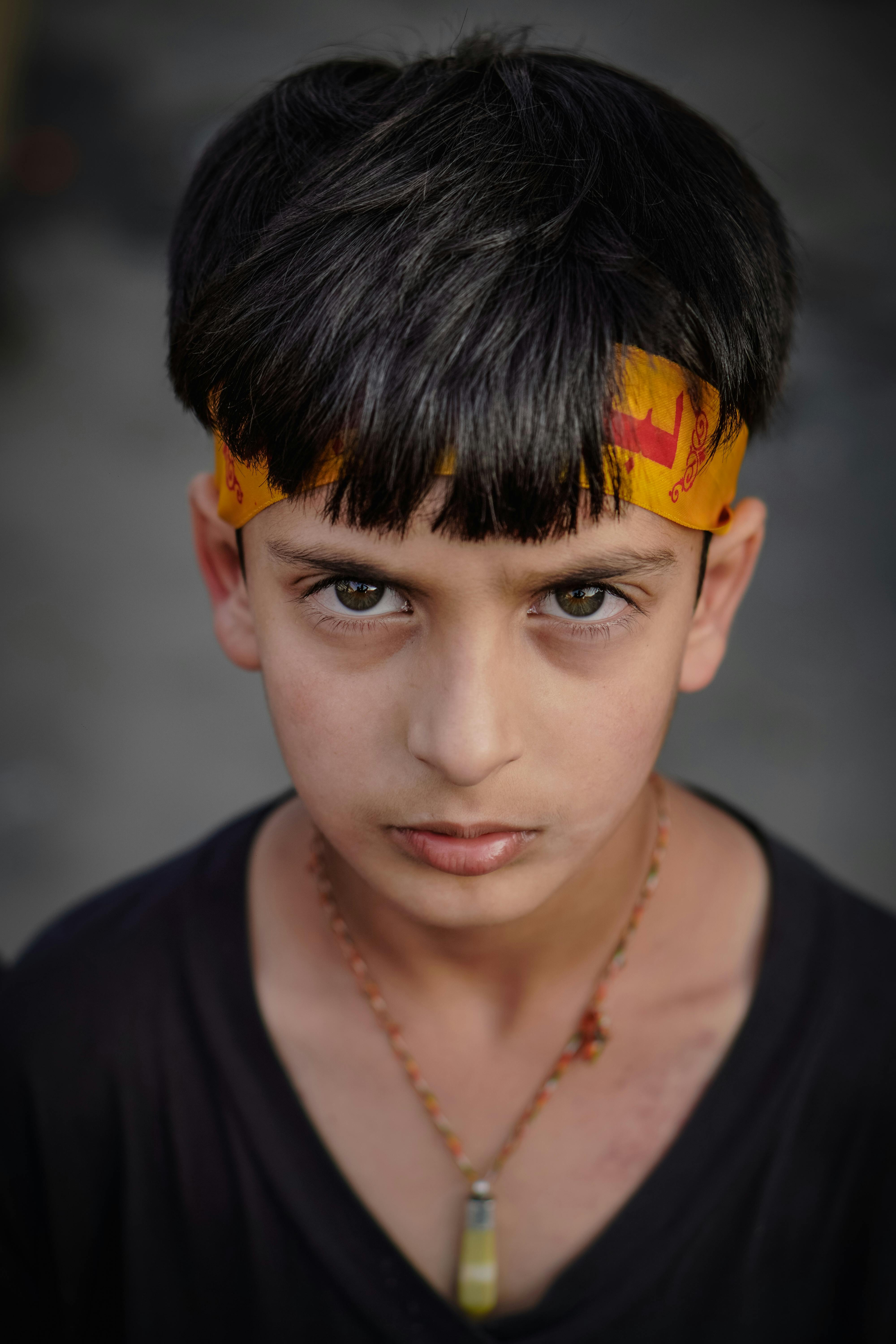 Free Close-up portrait of a young boy wearing a colorful headband, set against a blurred background. Stock Photo
