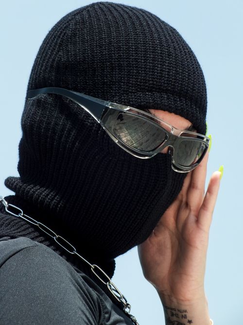Free Intriguing portrait of a stylish woman in a black balaclava with sunglasses, exuding mystery. Stock Photo