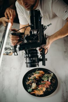 Photographer capturing a gourmet dish with high-end camera equipment from above.