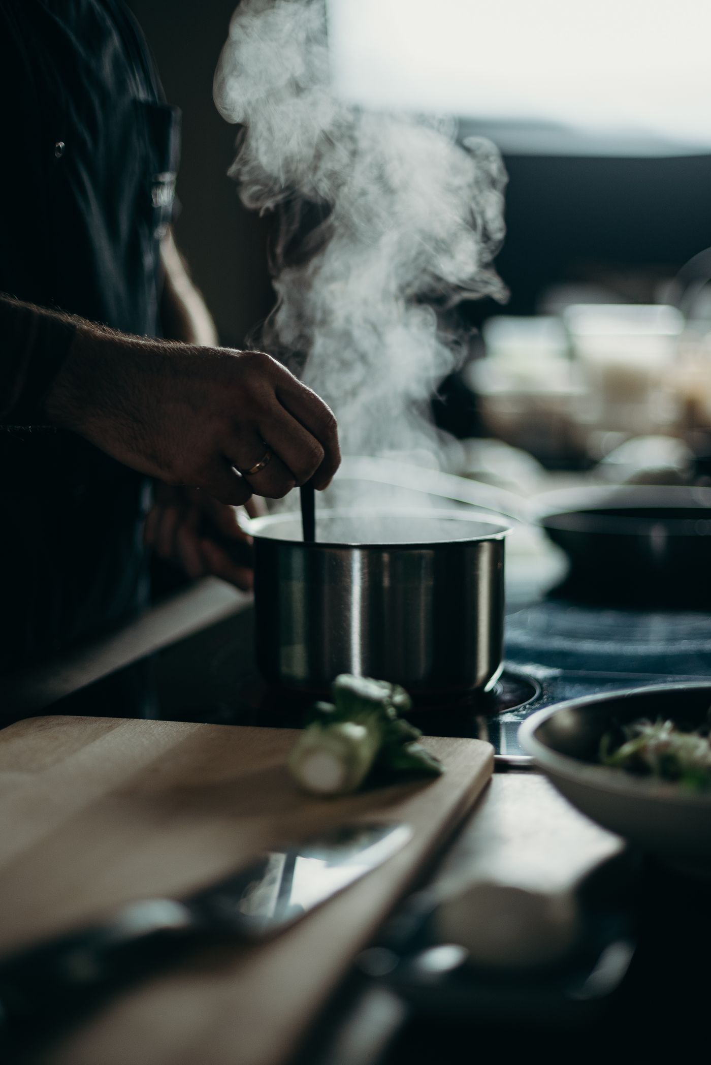 A person stirring a steaming pot, representing side-by-side cook testing between both appliances