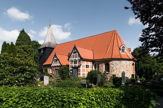 Scenic view of an old church with a red-tiled roof surrounded by lush greenery in Hamburg, Germany.