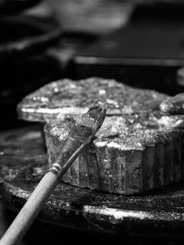 Black and white image of a brush resting on textured surface, showcasing artistic expression.