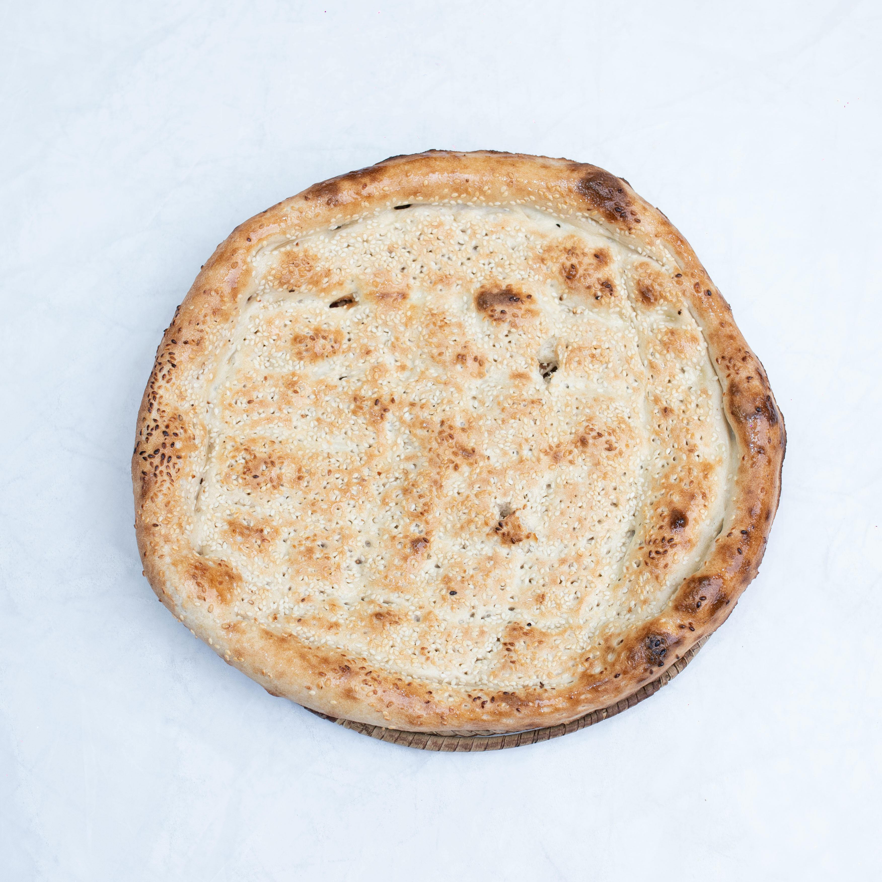 Flatbread with golden crust on a white backdrop, showcasing texture and color.