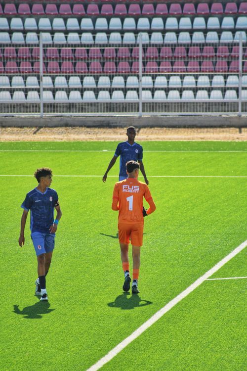 Free Three young soccer players on a green field discussing strategy during daylight. Stock Photo