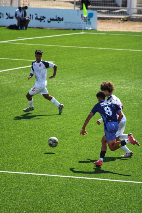 Free Teenagers playing an intense soccer match outdoors on a sunny day. Stock Photo