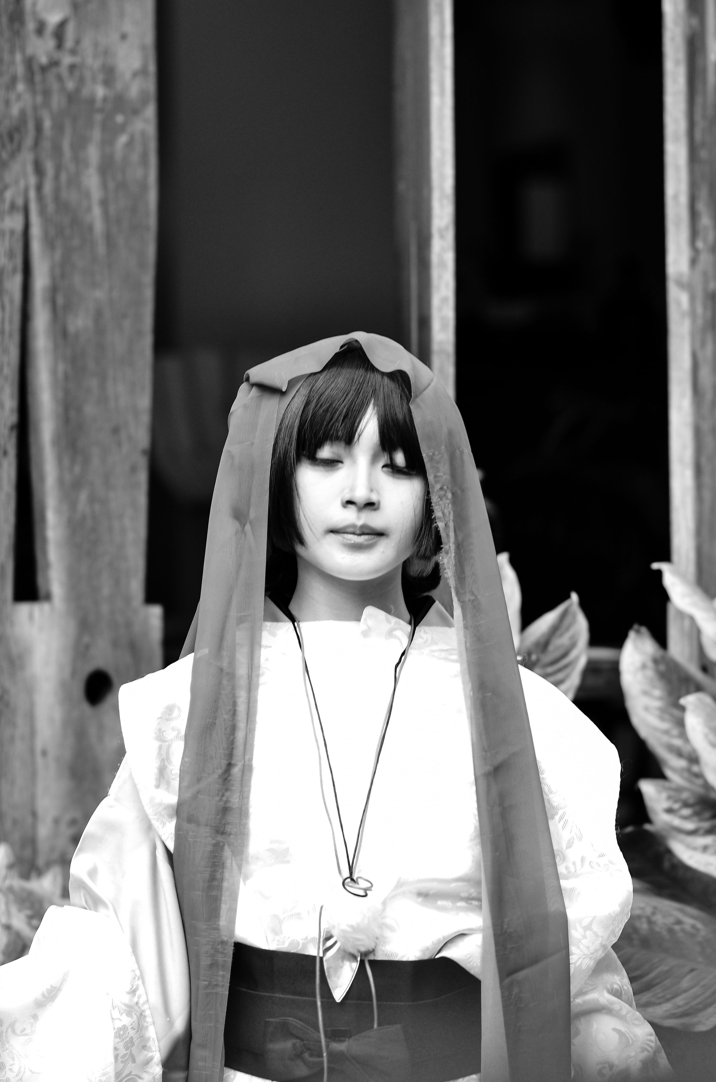 A striking black and white portrait captures a cosplayer in traditional attire, evoking elegance.