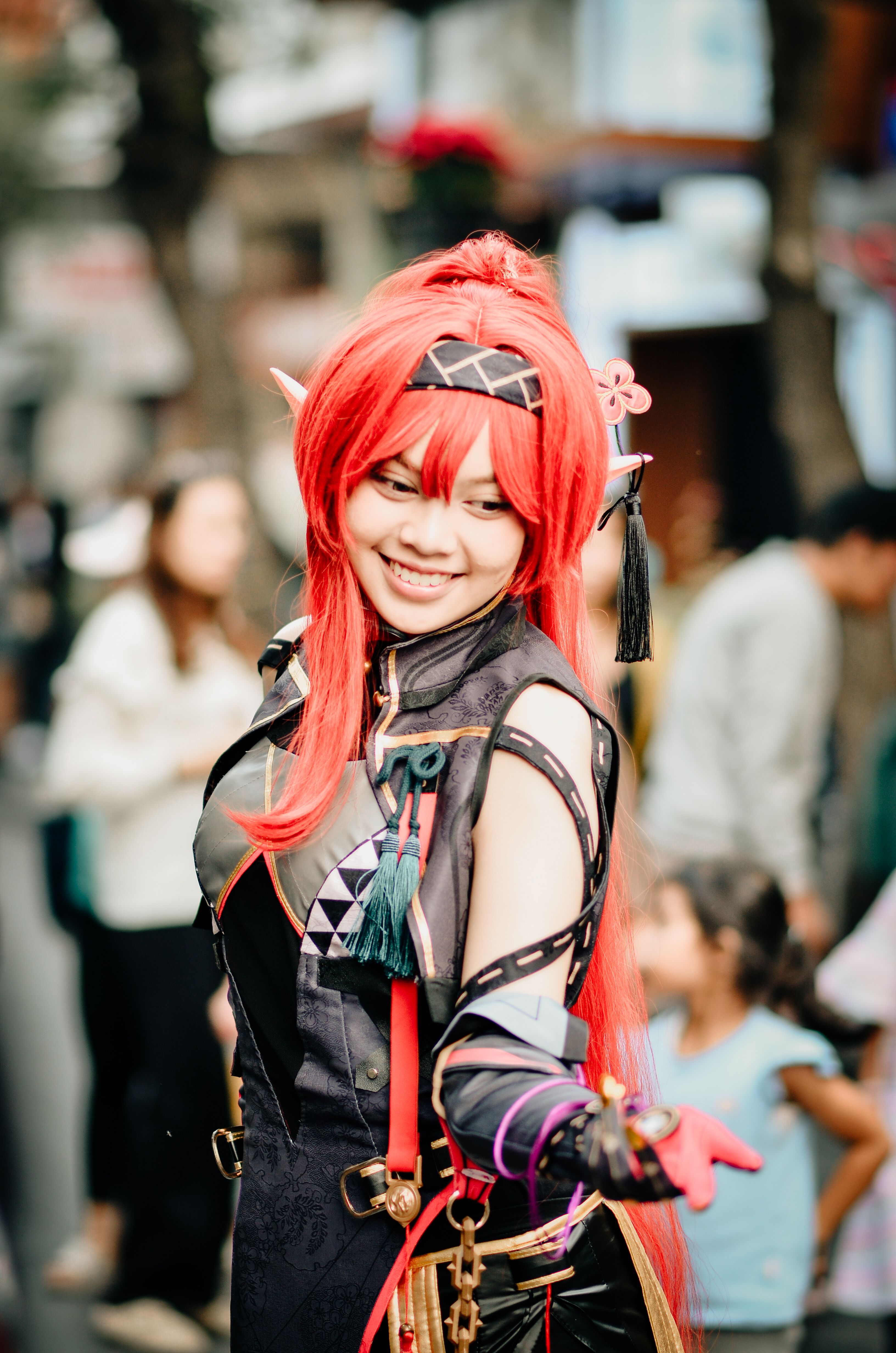 Smiling cosplayer in a vibrant costume at an outdoor event in Bandung, Indonesia.