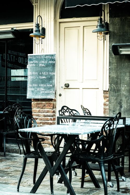Free Charming outdoor café with empty elegant black metal patio tables and chairs. Stock Photo