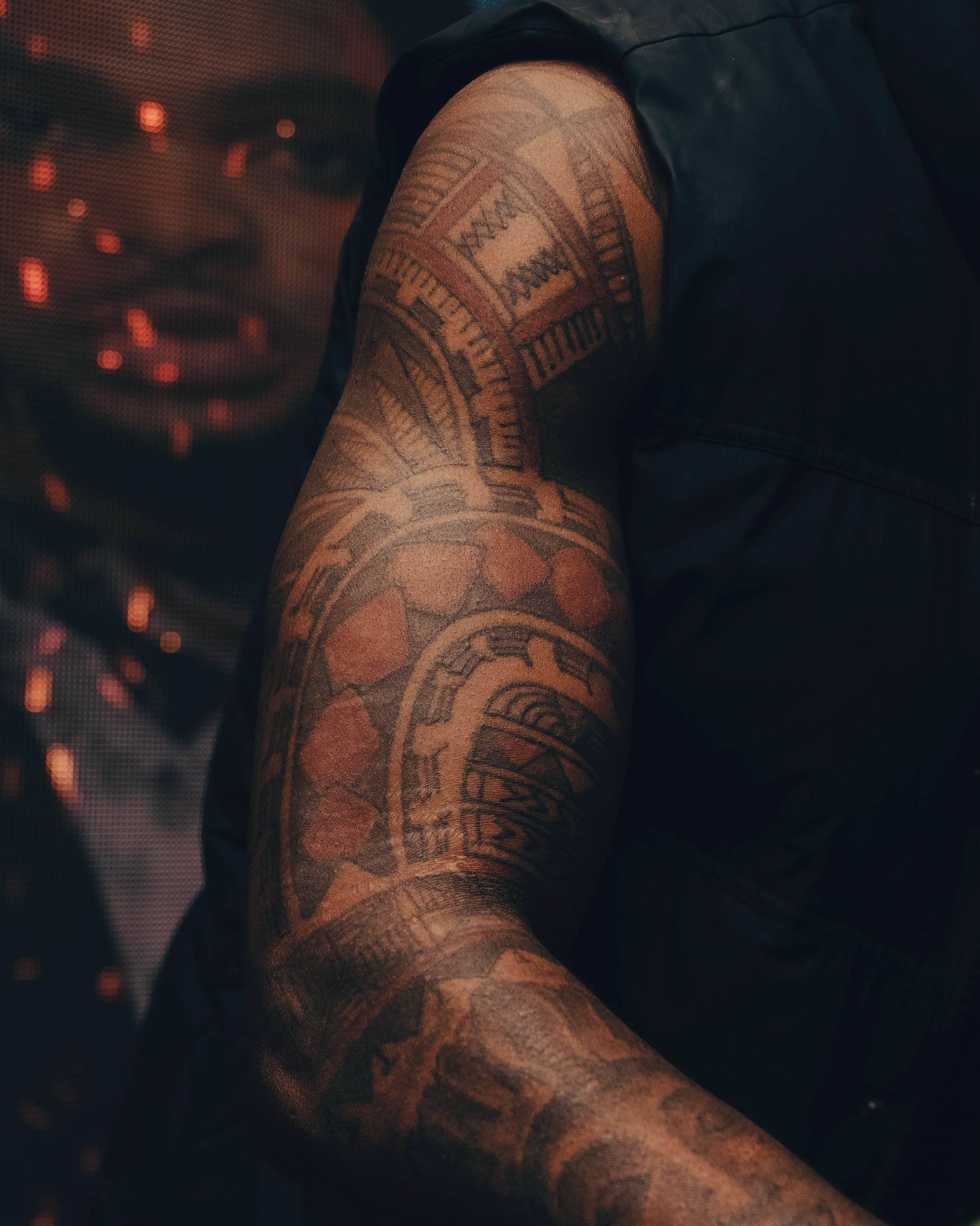 Close-up of a bold tribal blackwork sleeve with sharp geometric linework on the forearm