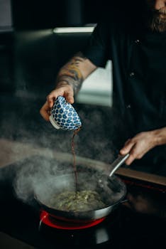 厨师小心翼翼地将酱汁倒入煎锅，烹制出一道热气腾腾的美味佳肴