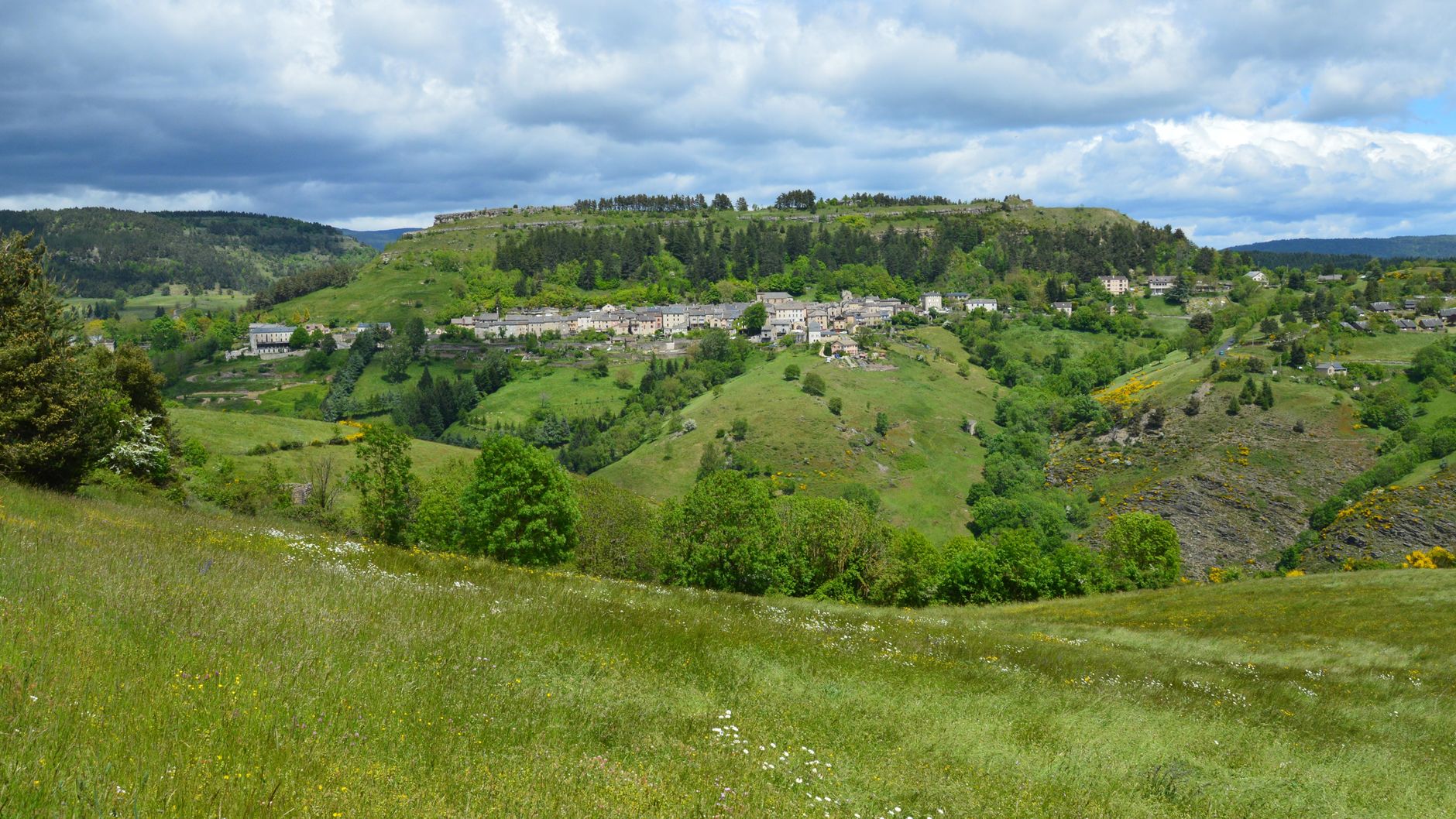 Picturesque landscape of Barre-des-Cévennes showing green hills and a village.