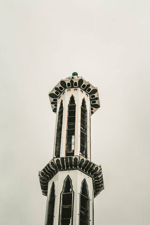 Free A tall, intricately designed minaret captured against an overcast sky, showcasing traditional Islamic architecture. Stock Photo
