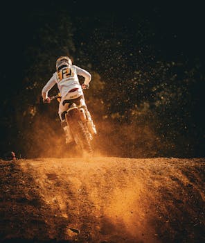 Dynamic motocross stunts captured at sunset, showcasing dirt flying as the rider speeds through the track.