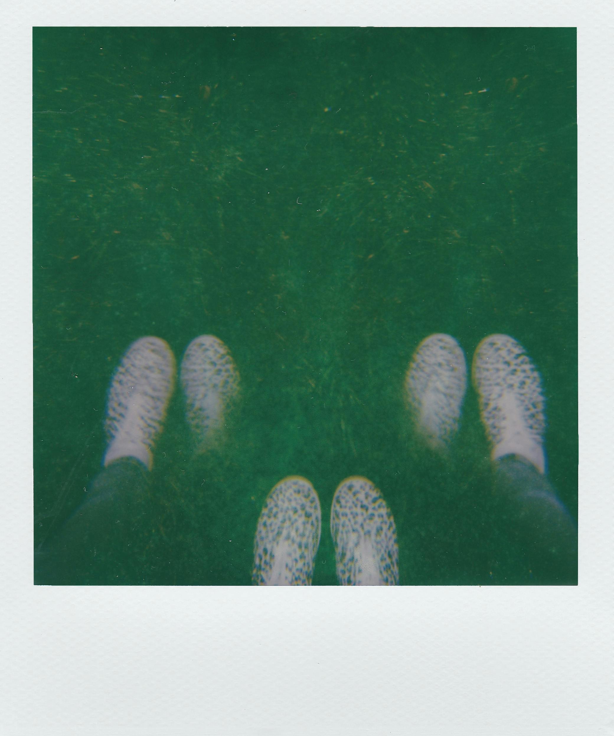 Blurred double exposure photo of sneakers on a grassy background.