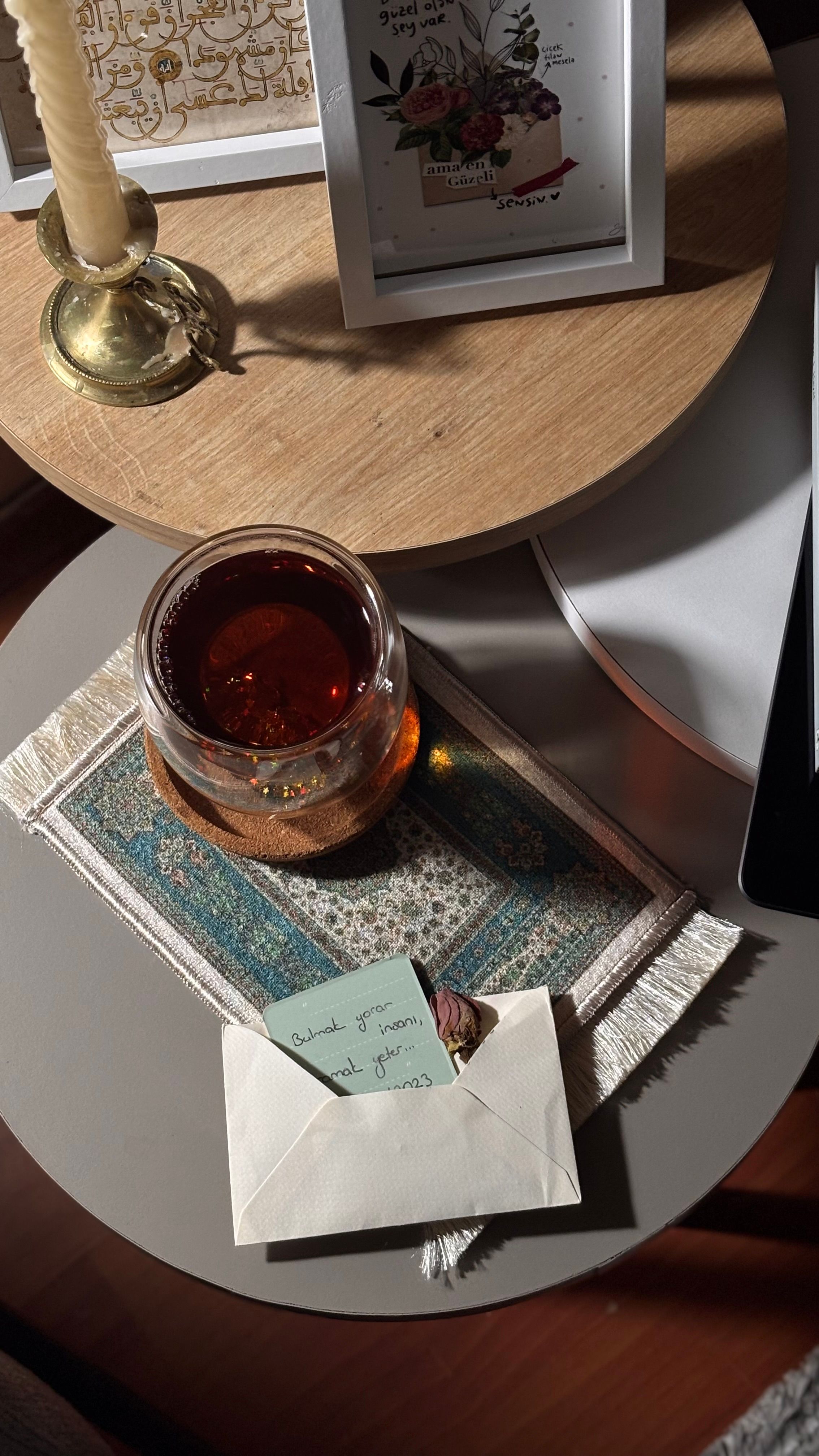 Warm tea setup with letter, candle, and decorative items in a cozy corner.